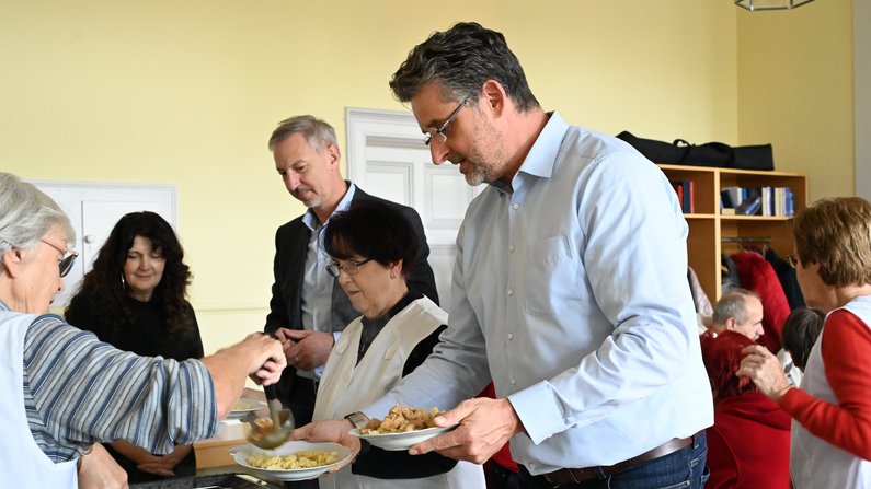 Auf dem Bild sind Personen zu sehen, die Essen verteilen. 